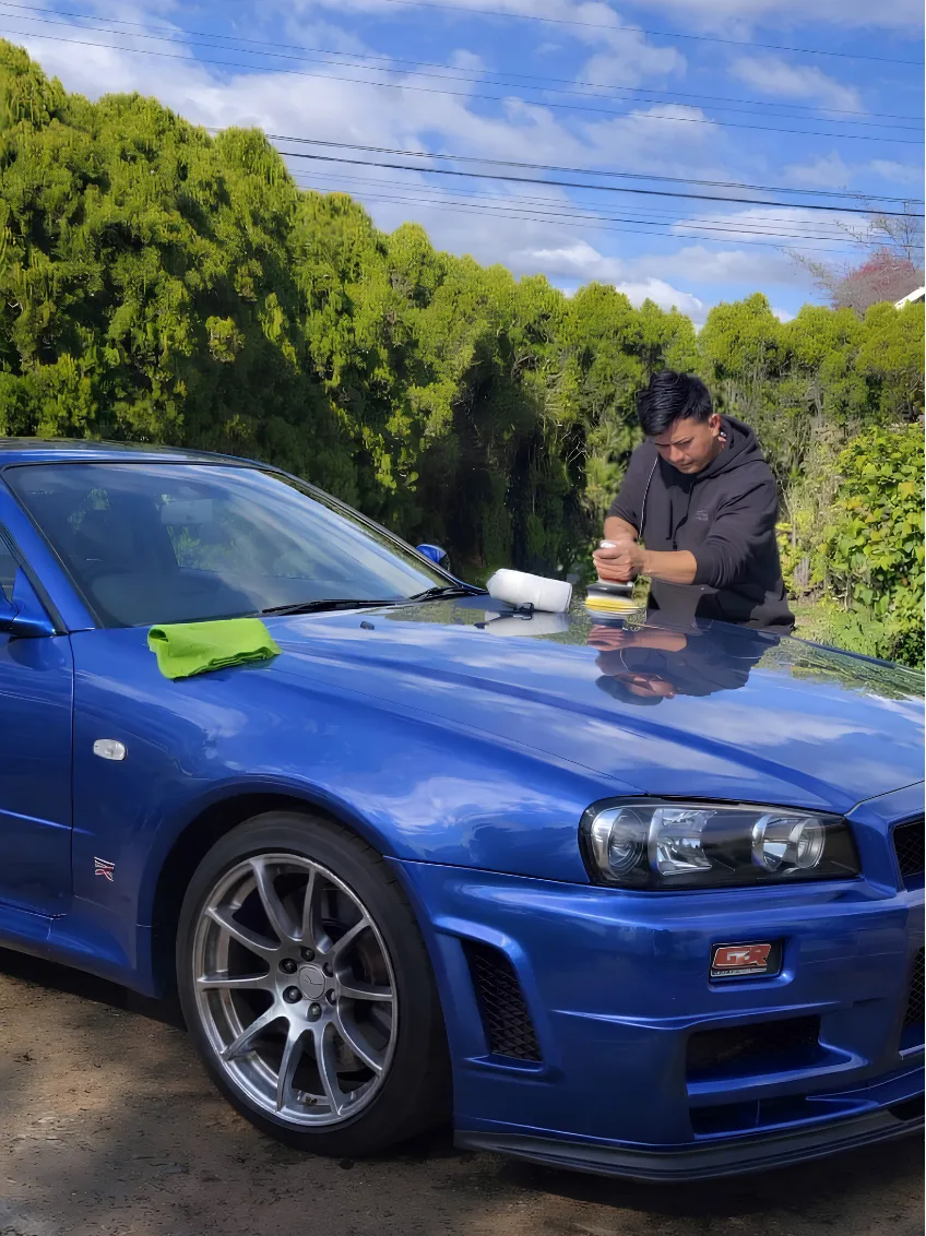 Benny machine-polishing a blue Nissan Skyline GT-R in a driveway